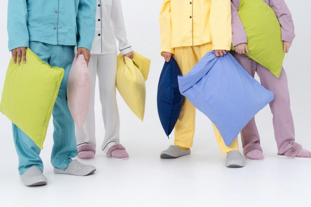A group of people in colorful pajamas holding pillows, ready for sleep or a pillow fight.
