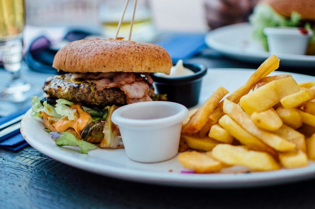 Close-up of classic junk food with burger, fries, and dipping sauces on a plate