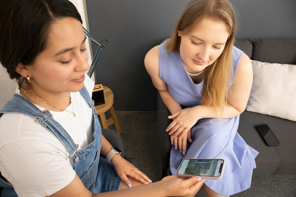 Two women discussing mental health support while looking at a phone indoors